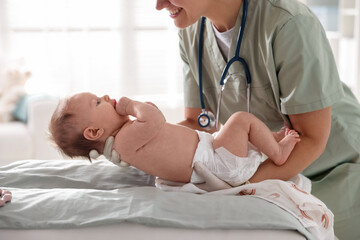 Obraz premium Pediatrician examining baby at table in clinic, closeup