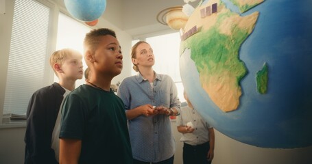 STEM Class: Female Teacher Explaining Renewable Energy Sources to Team of Smart Kids Using Earth...