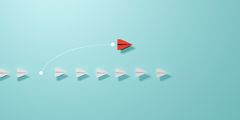 A red paper plane turns forward and overtakes a white paper plane on a light blue background, symbolizing leadership, innovation and divergent thinking. © Thawatchai Images