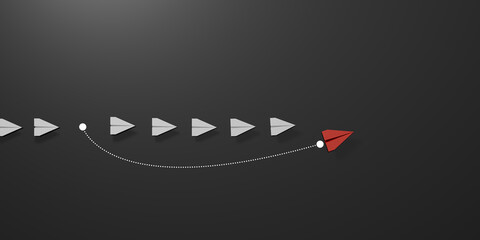 A red paper plane turns forward and overtakes a white paper plane on a light black background, symbolizing leadership, innovation and divergent thinking. © Thawatchai Images