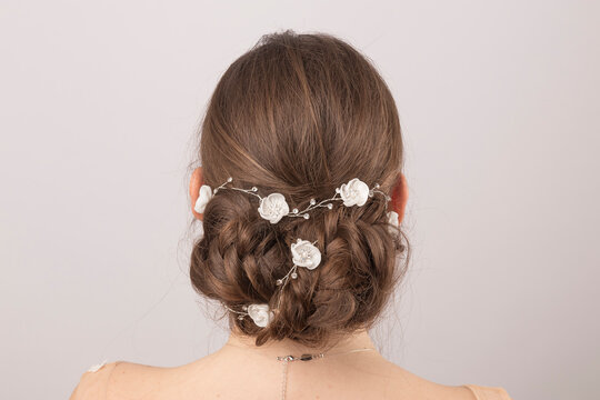 Elegant bridal tiara adorning the meticulously styled hair of a young bride, seen from behind, against a soft grey studio backdrop