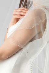 Elegant bridal veil on a young girl, seen from behind, against a soft grey studio backdrop