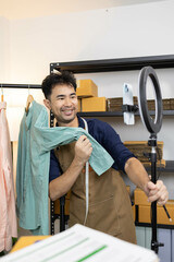 A man is selling clothes online. He has a notebook to record information. He is wearing a blue...