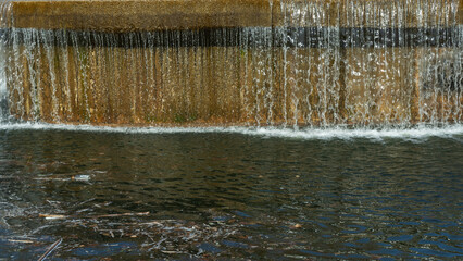 An artificial waterfall on a city canal creates a stunning blend of urban design and natural...