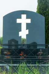 Tombstone with a cross cut through symbolizing faith in a peaceful cemetery. Light streaming...
