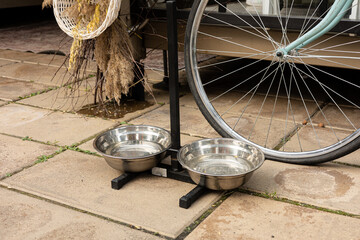 Stainless steel bowls on a raised stand, providing water for pets in an outdoor patio setting....