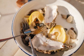 Fresh oysters on ceramic plate with lemon wedges served for gourmet dining