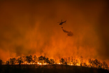 Fire fighting helicopter carry watethar bucket to extinguish the forest fire.