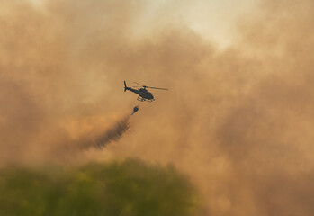 Fire fighting helicopter carry watethar bucket to extinguish the forest fire.