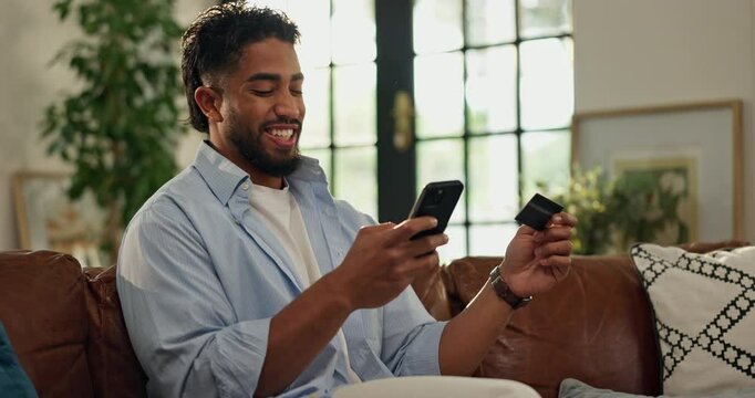 Man, typing and phone with credit card on sofa for mortgage payment, easy transaction and debt free. Excited, person and relief with smartphone in house for electronic transfer and loan settlement