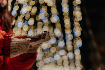 Closeup cropped shot of woman typing on mobile phone at dark night city street on blurred...
