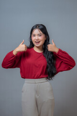 Portrait of a cheerful young Indonesian woman with long black hair, wearing a red blouse and beige...