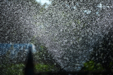 Watering plants in summer, water drops in the air under the sun