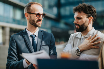 Two men engaged in a conversation outdoors, dressed professionally, with a focus on communication.
