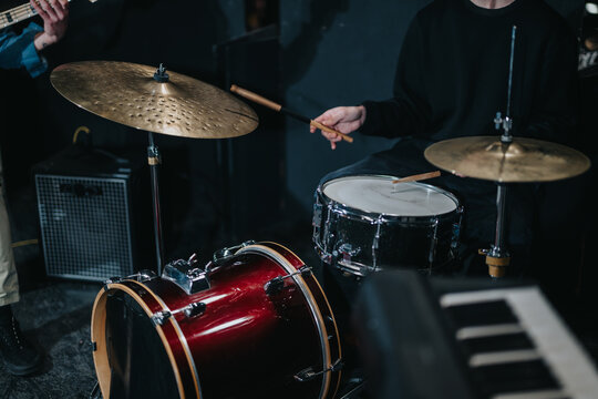 A close-up view of a drummer playing during a live music performance, highlighting drum set details and cymbals for a rhythmic, artistic vibe.