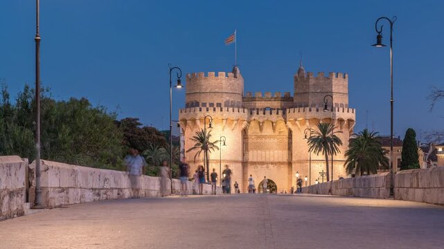 Serrans Towers (Torres de Serranos) day to night transition timelapse in Valencia, Spain. A grand medieval gate from the city's ancient walls. People walking on a bridge near historic landmark