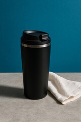 Obraz premium A sleek, black travel mug, placed on a modern surface