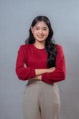 Portrait of a confident young Indonesian woman with long black wavy hair, wearing a red long-sleeve...