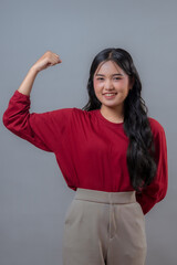 Confident young Asian Indonesian woman wearing a red long-sleeve shirt and beige pants showing...