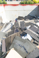 Roofing shingles damaged by hailstorm in garbage bin