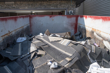 Roofing shingles damaged by hailstorm in garbage bin