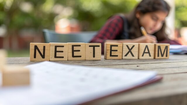 Blurred background with sharp focus on wooden blocks spelling NEET exam concept
