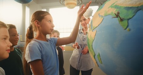 STEM Science Lesson: Smart School Girl Presenting Renewable Energy Sources Using Globe with 3D...