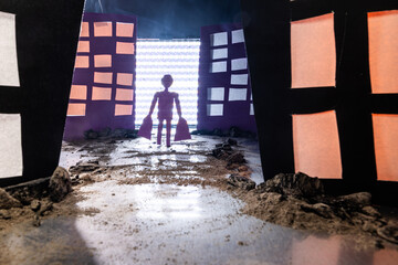 Conceptual image of a man carrying shopping bags walking on a dirt and rock-covered path through a...