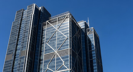 Fototapeta premium Bold architectural shot of a glass-and-metal skyscraper against a clear blue sky