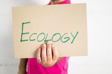 man in a pink t-shirt showing an eco-awareness poster