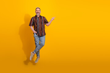 Stylish mature man posing in vibrant outfit with cheerful expression against a bright yellow background expressing happiness