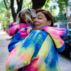 Woman and dachshund dog dressed alike in colorful tie-dye outdoors