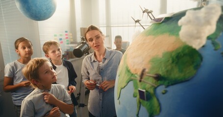 Ecology STEM Class: Elementary School Boy Attaching Miniature Model of Wind Turbine to Globe....