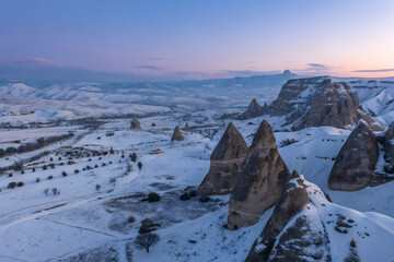 Aerial view of rough rock formations covered with white snow against cloudless evening sky