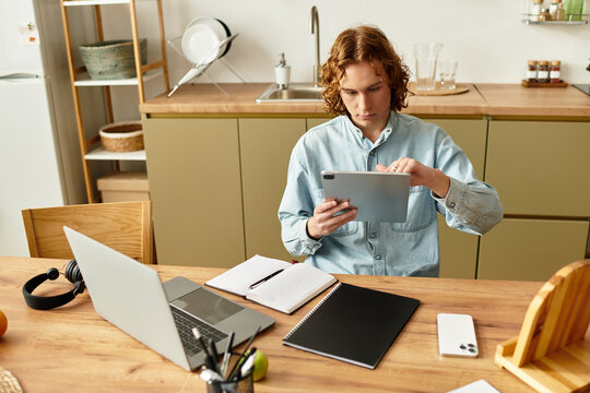 Focused young man engaging with tablet at home workspace during the day