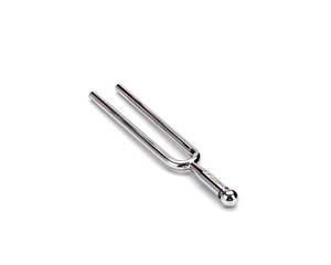 Shiny metal tuning fork lies on white background, reflecting light off its polished surface. simple...