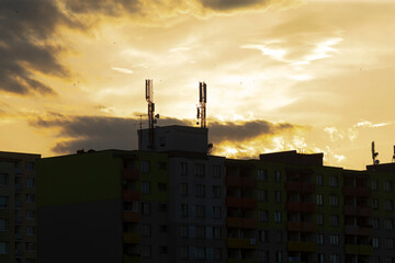The urban buildings sharply contrast with the numerous communication towers at sunset, showcasing...