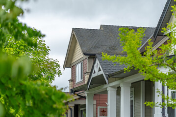 Top of grey stucco luxury house with shingle roof, green trees and nice windows in Spring in Vancouver, Canada, North America. Day time on May 2025.