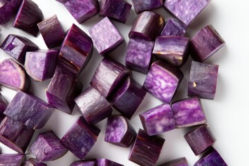 Diced purple sweet potatoes with white flecks on a plain, minimalist white surface