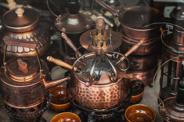 Copper fondue set and Vintage Utensils. Utensils arranged in rich detail with warm reflections and textures. Concept of traditional craftsmanship, timeless kitchen style