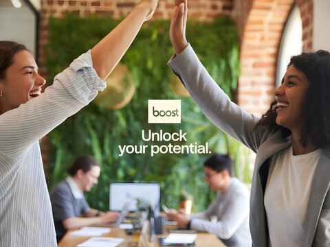 Two Smiling Women High Fiving in an Office with Two People Working at Desks in the Background - Powered by Adobe