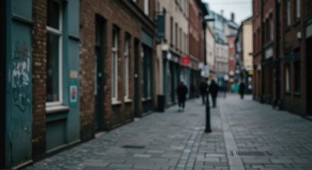 Fototapeta premium A blurred urban alleyway, featuring brick buildings and people walking