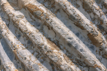Spiral sculptural relief on the surface of a column in the ancient city of Perge in Turkey. Antique columns subject to erosion and ruins of an ancient city. Background of the column surface.