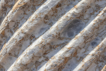 Spiral sculptural relief on the surface of a column in the ancient city of Perge in Turkey. Antique columns subject to erosion and ruins of an ancient city. Background of the column surface.