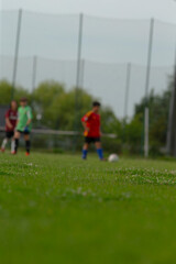 On a vibrant soccer field, numerous players are actively preparing for an exciting match, with a special focus on a young, energetic athlete skillfully dribbling the ball near the goal area