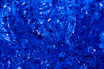 Abstract blue foil texture with shiny and crinkled surface capturing light in unique patterns