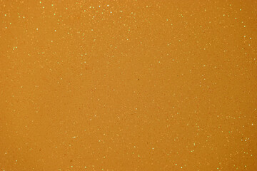 Sparkling golden surface with shimmering particles captured under bright light in a creative setting