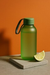 A refreshing drink bottle with a lemon slice on the stone, suggesting a healthy and invigorating beverage. The green bottle and lime complement each other nicely