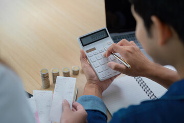Expense Management and Budgeting. Young couple calculating finances with receipts and coins.