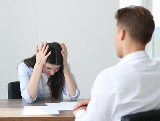 Young woman complaining to man at wooden table indoors